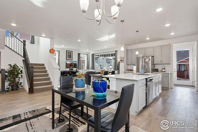 dining room with sink, an inviting chandelier, and light hardwood / wood-style flooring