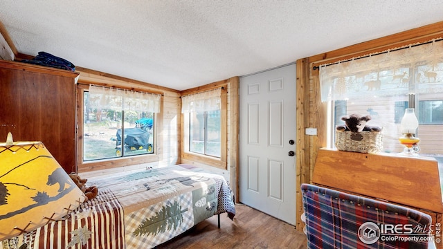 bedroom with hardwood / wood-style flooring, wooden walls, and a textured ceiling