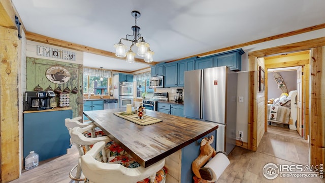 kitchen featuring pendant lighting, blue cabinetry, appliances with stainless steel finishes, an inviting chandelier, and light wood-type flooring