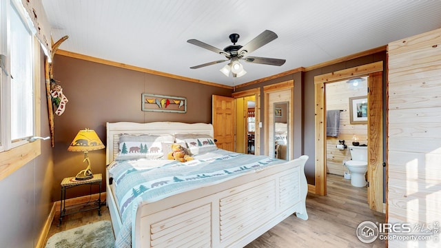 bedroom featuring ensuite bath, wooden walls, ornamental molding, and light wood-type flooring