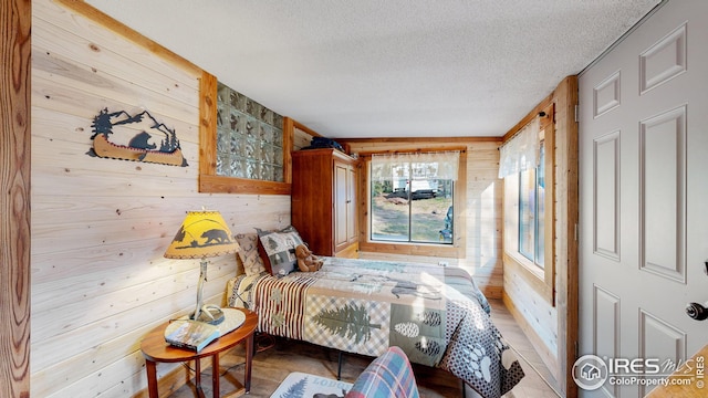 bedroom with a textured ceiling and wood walls