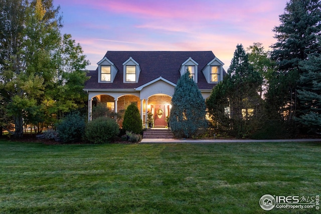 cape cod-style house with a lawn