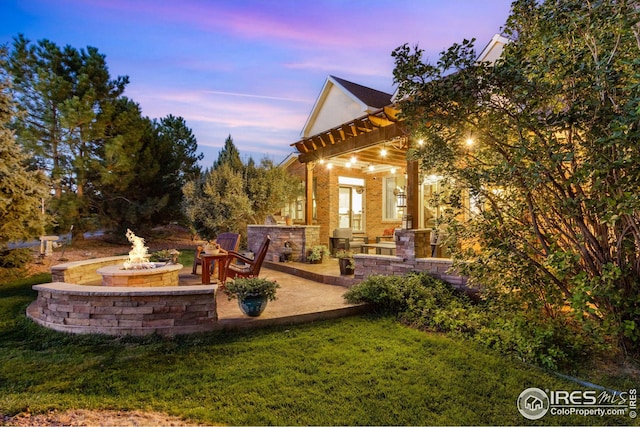 yard at dusk featuring a patio and a fire pit