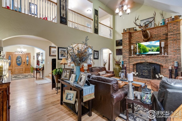 living room featuring a notable chandelier, a towering ceiling, and light hardwood / wood-style flooring