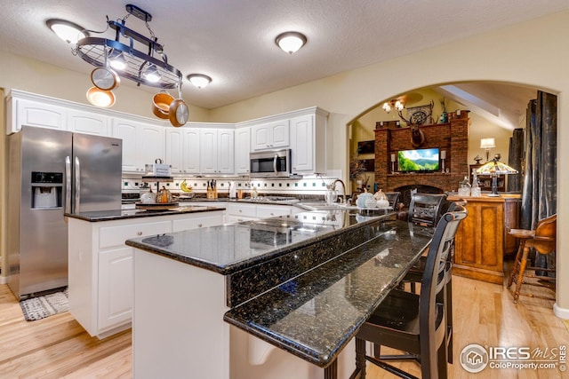 kitchen with stainless steel appliances, dark stone counters, a kitchen island, and white cabinets