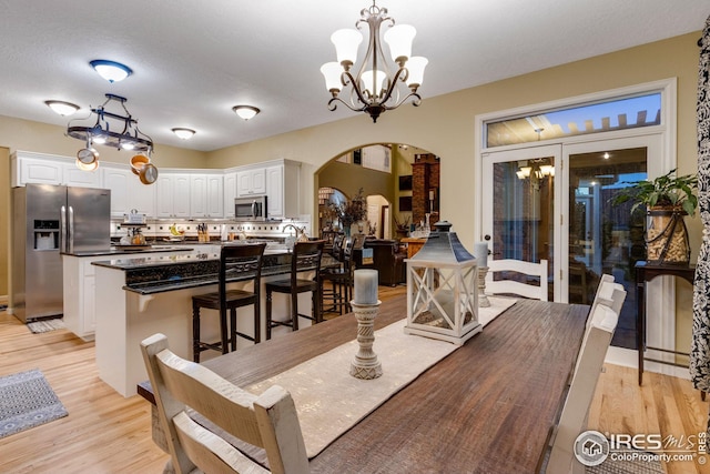 dining space with a notable chandelier and light hardwood / wood-style floors