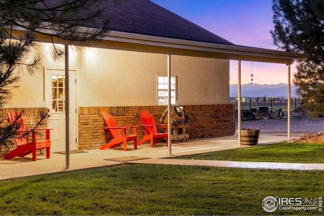 patio terrace at dusk with a mountain view and a lawn