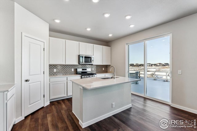 kitchen with white cabinetry, sink, stainless steel appliances, and a center island with sink