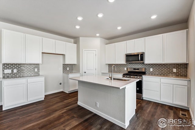 kitchen featuring sink, white cabinetry, appliances with stainless steel finishes, dark hardwood / wood-style flooring, and a kitchen island with sink