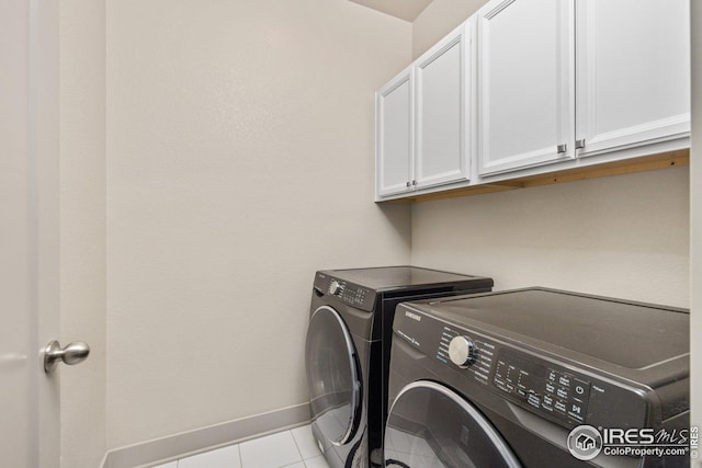 laundry area featuring cabinets, washer and dryer, and light tile patterned flooring