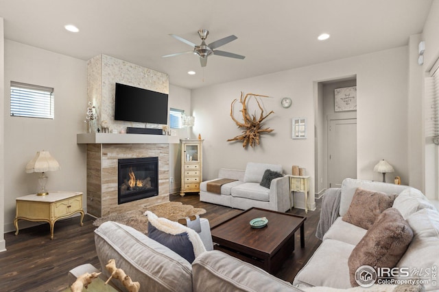 living room featuring a tiled fireplace, dark hardwood / wood-style floors, and ceiling fan