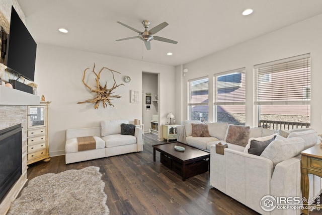 living room featuring a tiled fireplace, dark hardwood / wood-style floors, and ceiling fan