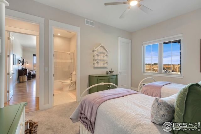 carpeted bedroom with ceiling fan, baseboards, visible vents, and ensuite bathroom