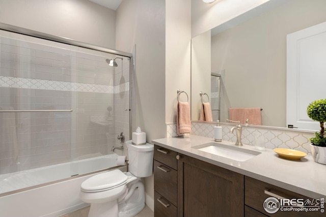 bathroom with vanity, toilet, bath / shower combo with glass door, and tasteful backsplash