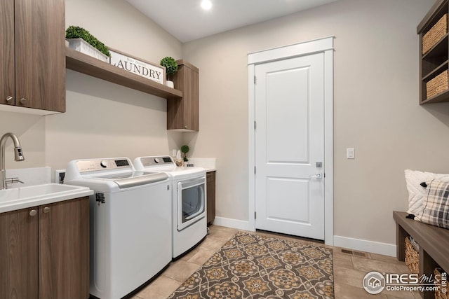 washroom featuring a sink, baseboards, washing machine and dryer, and cabinet space