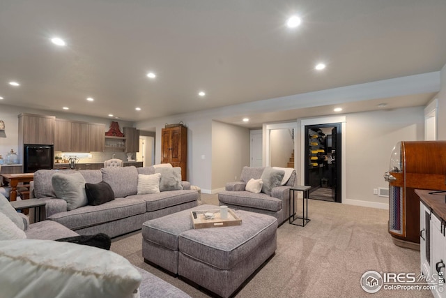 living area with baseboards, recessed lighting, and light carpet