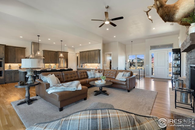 living room with recessed lighting, a fireplace, a ceiling fan, and light wood-type flooring