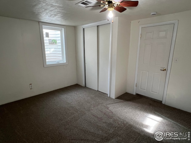 unfurnished bedroom featuring ceiling fan, carpet floors, a closet, and a textured ceiling