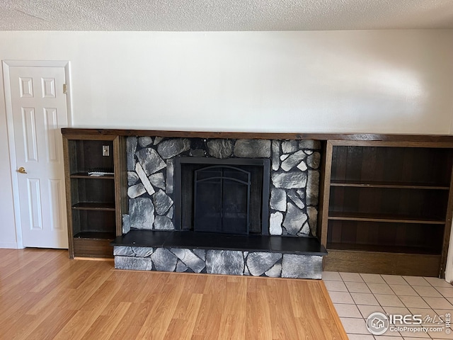 details with a stone fireplace, wood-type flooring, and a textured ceiling