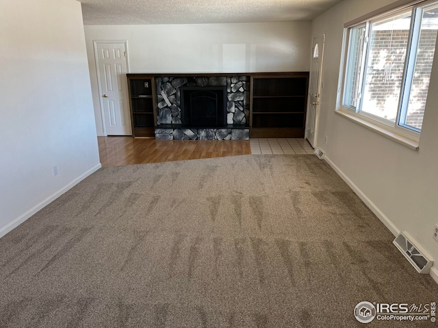 unfurnished living room with a fireplace, a healthy amount of sunlight, carpet flooring, and a textured ceiling