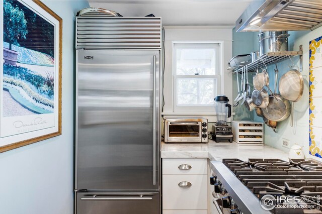 kitchen with white cabinets, light stone countertops, appliances with stainless steel finishes, and a toaster