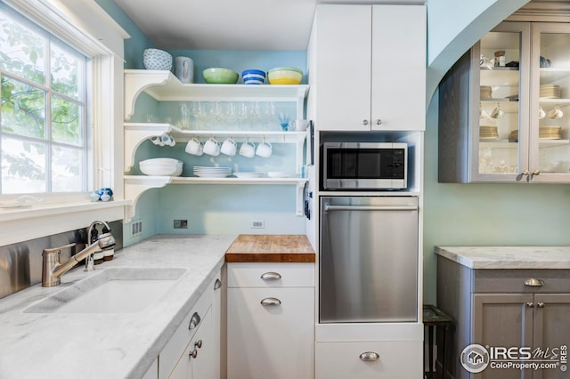 kitchen with white cabinetry, sink, and light stone counters