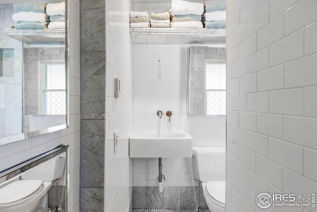 half bathroom with toilet and tile walls