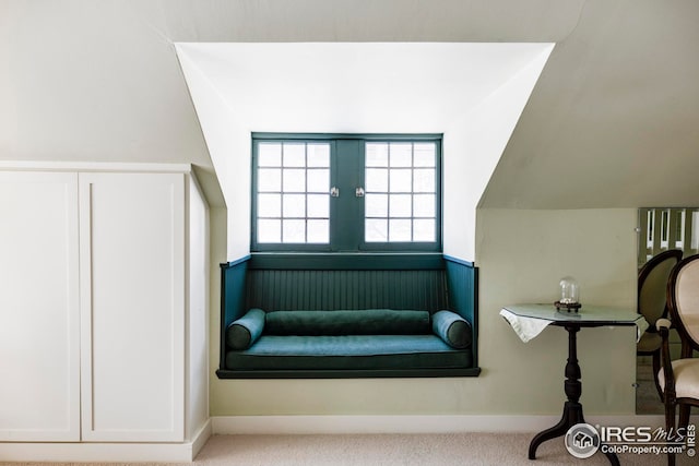 living area featuring light carpet and vaulted ceiling