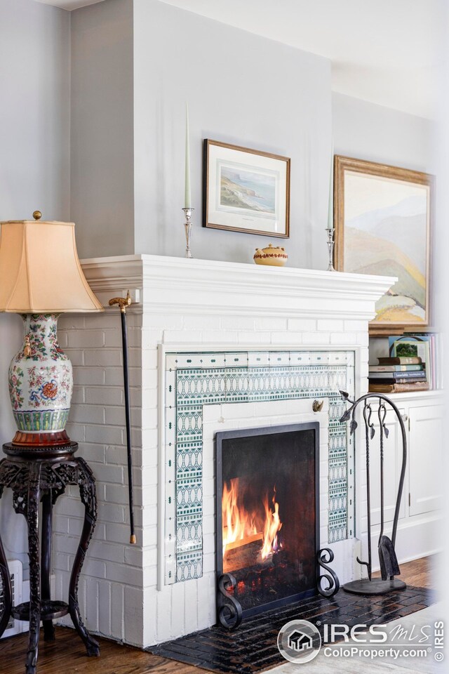 details featuring a tiled fireplace and wood finished floors