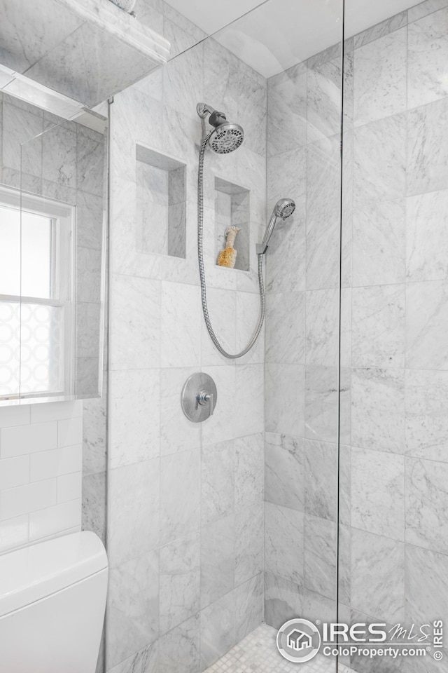 bathroom featuring a tile shower and toilet