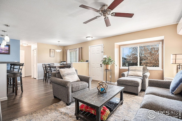 living room featuring hardwood / wood-style flooring, a textured ceiling, and ceiling fan