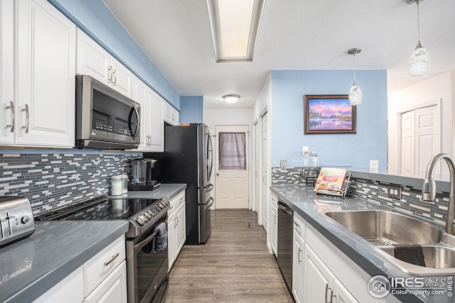 kitchen with sink, hanging light fixtures, appliances with stainless steel finishes, dark hardwood / wood-style floors, and white cabinets