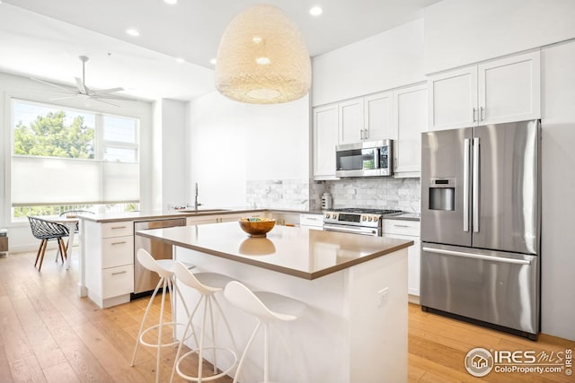 kitchen featuring white cabinetry, sink, a center island, kitchen peninsula, and stainless steel appliances