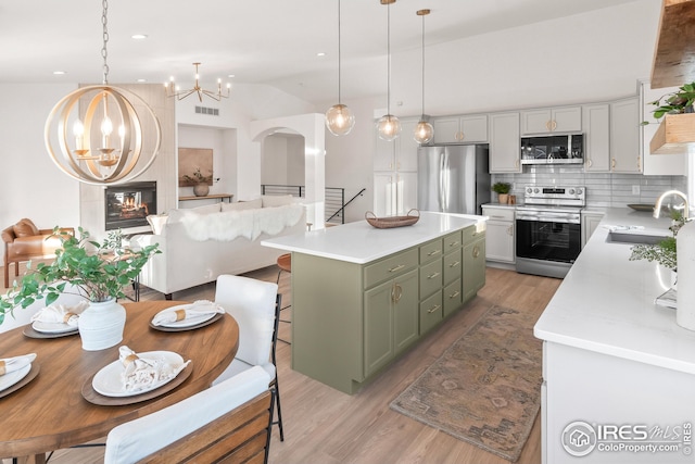 kitchen with a notable chandelier, stainless steel appliances, light countertops, green cabinets, and a sink