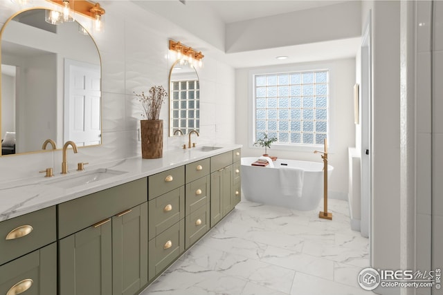 full bathroom with marble finish floor, double vanity, a soaking tub, and a sink