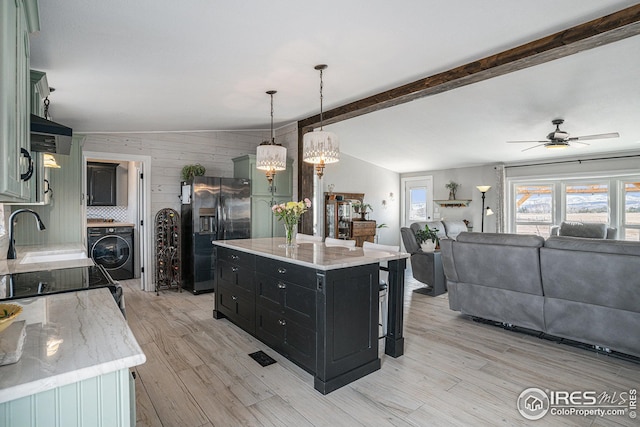 kitchen with sink, a center island, stainless steel refrigerator with ice dispenser, washer / clothes dryer, and decorative light fixtures