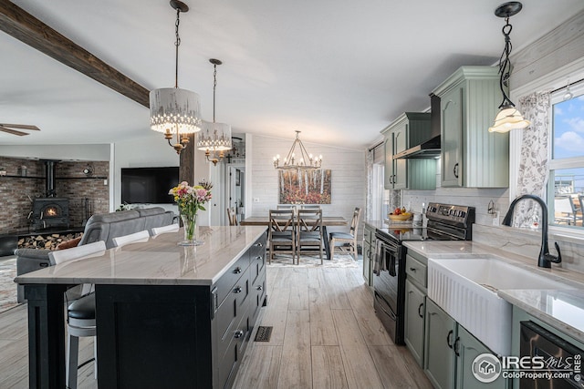 kitchen with black range with electric cooktop, decorative light fixtures, light stone countertops, and a wood stove