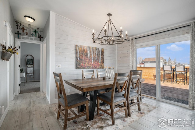 dining room featuring wood walls, wood-type flooring, and a notable chandelier