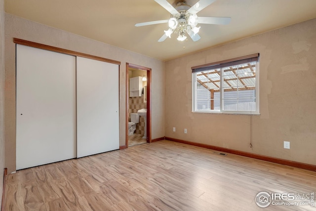 unfurnished bedroom featuring connected bathroom, light hardwood / wood-style floors, a closet, and ceiling fan