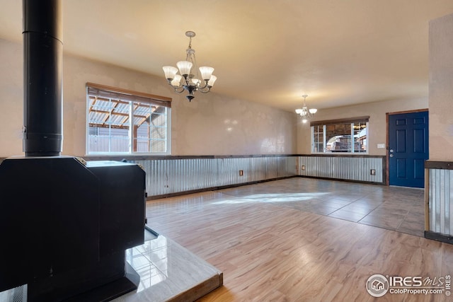 interior space featuring hardwood / wood-style flooring, a wealth of natural light, a chandelier, and a wood stove