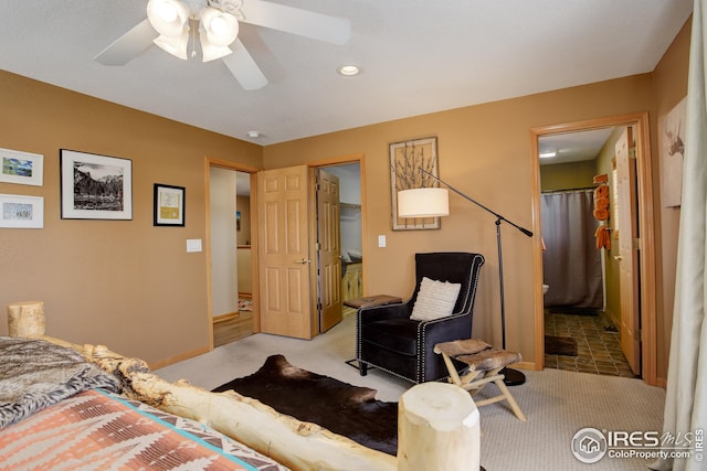 carpeted bedroom with ensuite bath, a walk in closet, and ceiling fan