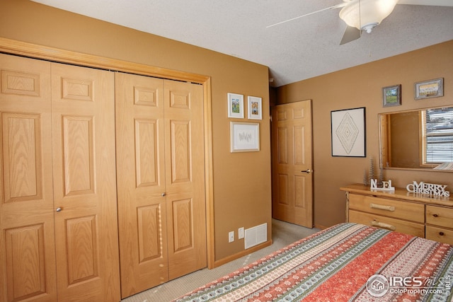 carpeted bedroom with ceiling fan, a closet, and a textured ceiling