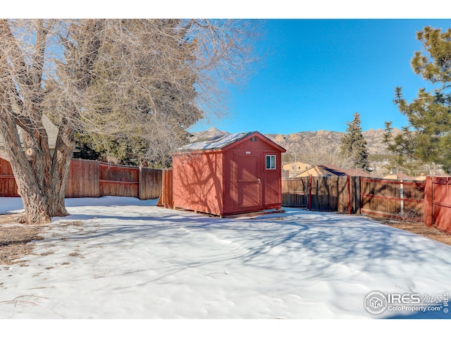 yard covered in snow featuring a mountain view and a storage shed