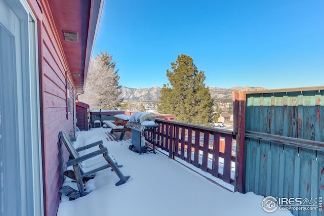 snow covered back of property featuring a mountain view and a grill