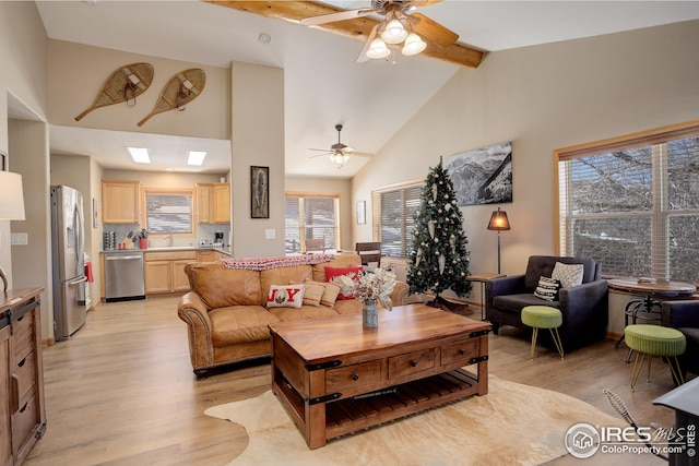 living room with beam ceiling, ceiling fan, sink, and light wood-type flooring