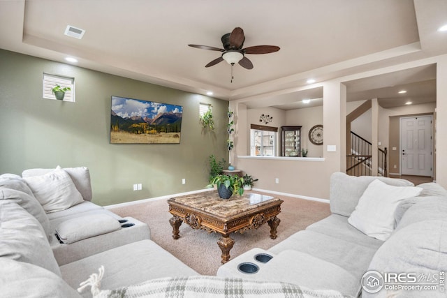 living room with ceiling fan, a tray ceiling, and carpet floors