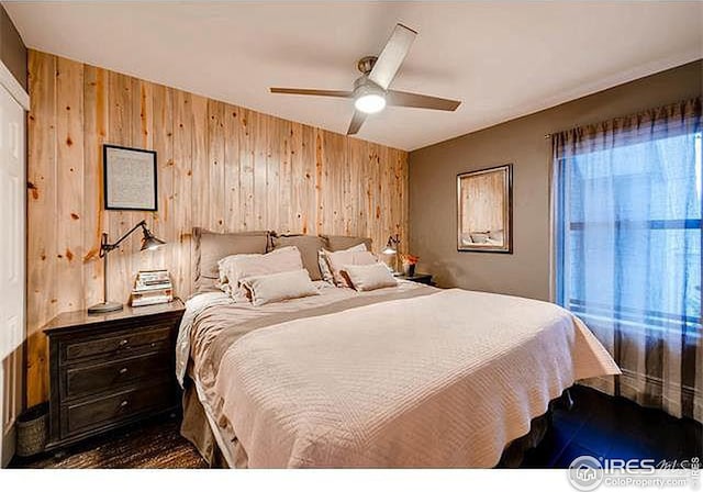 bedroom featuring ceiling fan and wooden walls