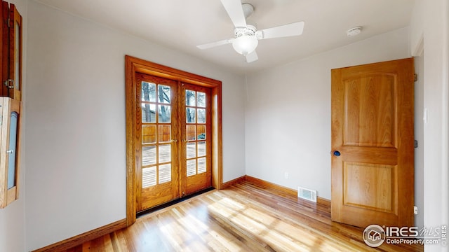 empty room with ceiling fan, light wood-type flooring, and french doors