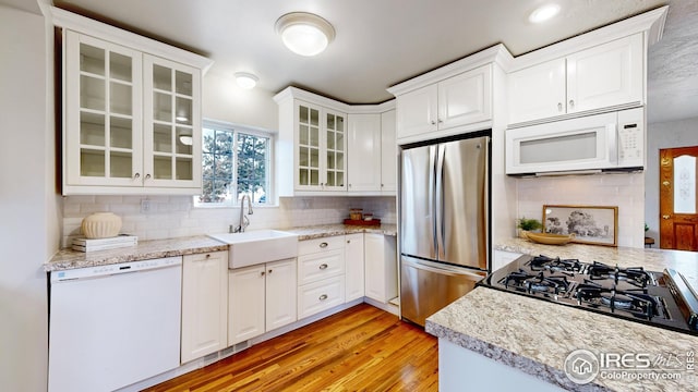 kitchen with white cabinetry, sink, light hardwood / wood-style flooring, and appliances with stainless steel finishes