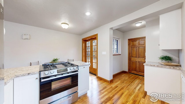 kitchen featuring white cabinetry, stainless steel gas range, and light hardwood / wood-style floors